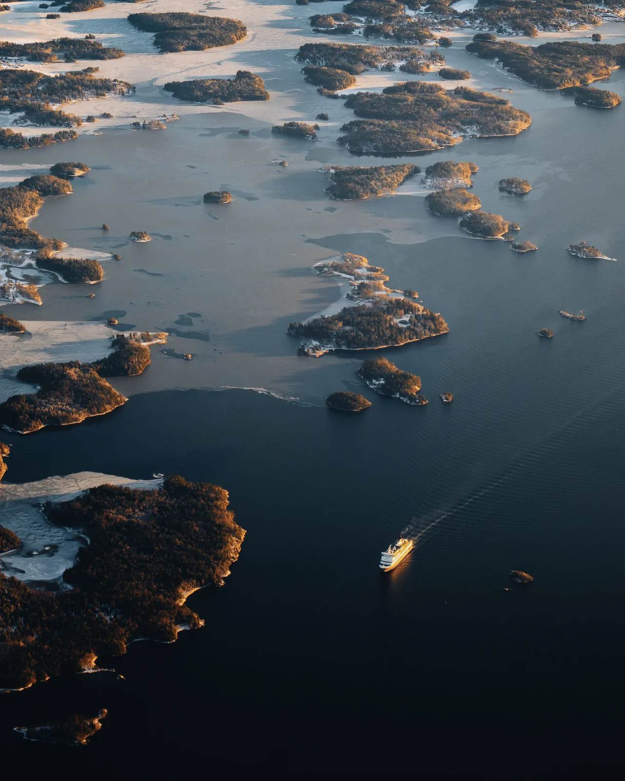 An archipelago from the air, partly iced over, with a ferry in open water